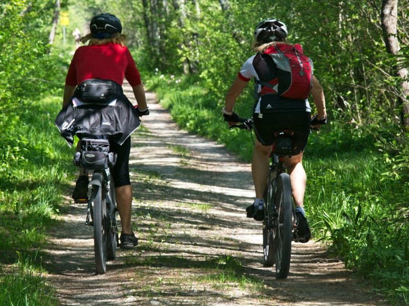 Na zdjęciu dwójka rowerzystów na ściezce rowerowej w lesie