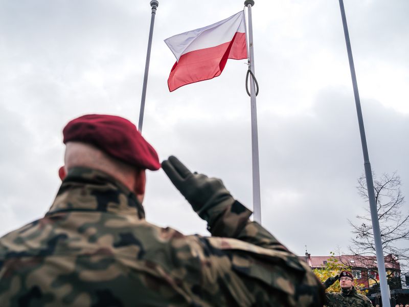 Na zdjęciu żołnierz salutujący fladze narodowej