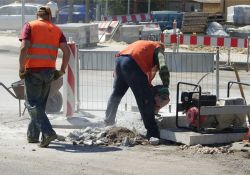 Na zdjęciu roboty drogowe. Drogowcy wykonujacy prace przy użyciu narzędzi do prac drogowych: młot, taczki itp.